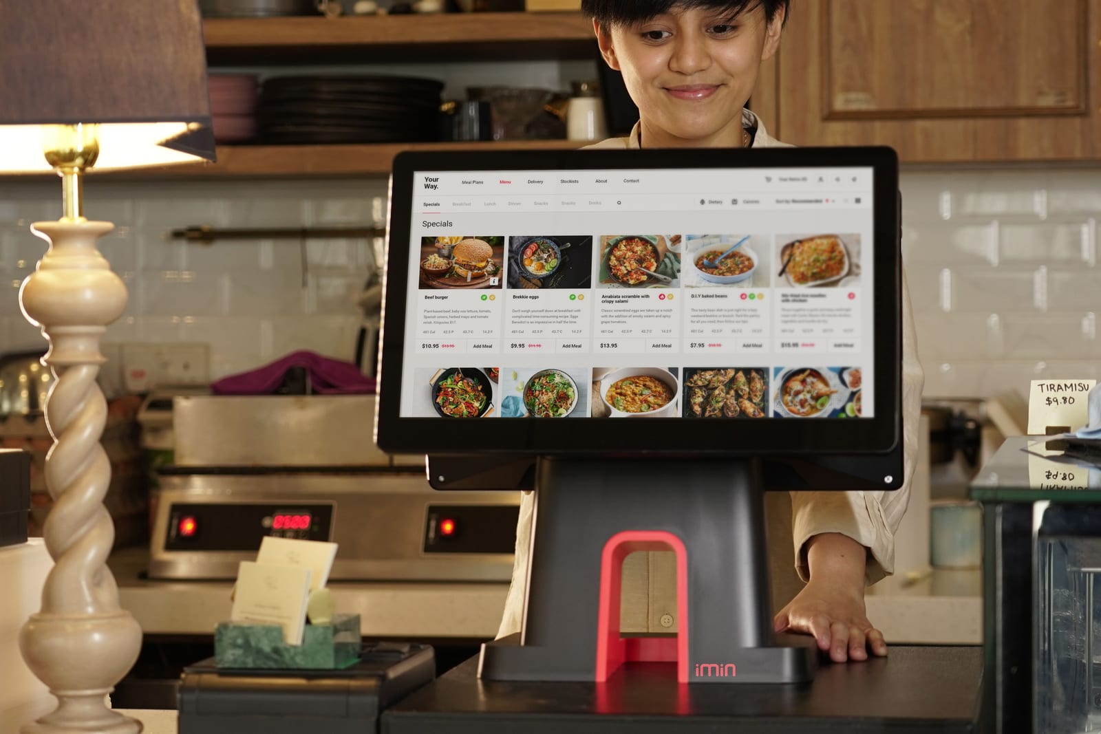 Cashier uses touchscreen POS system in busy restaurant