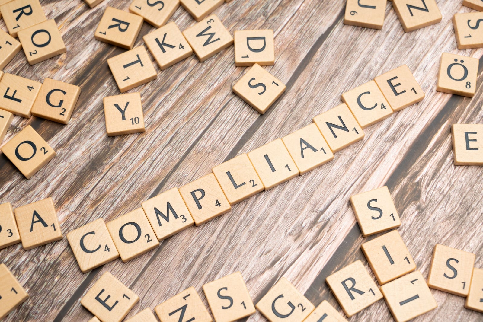 Wooden letter tiles spelling compliance