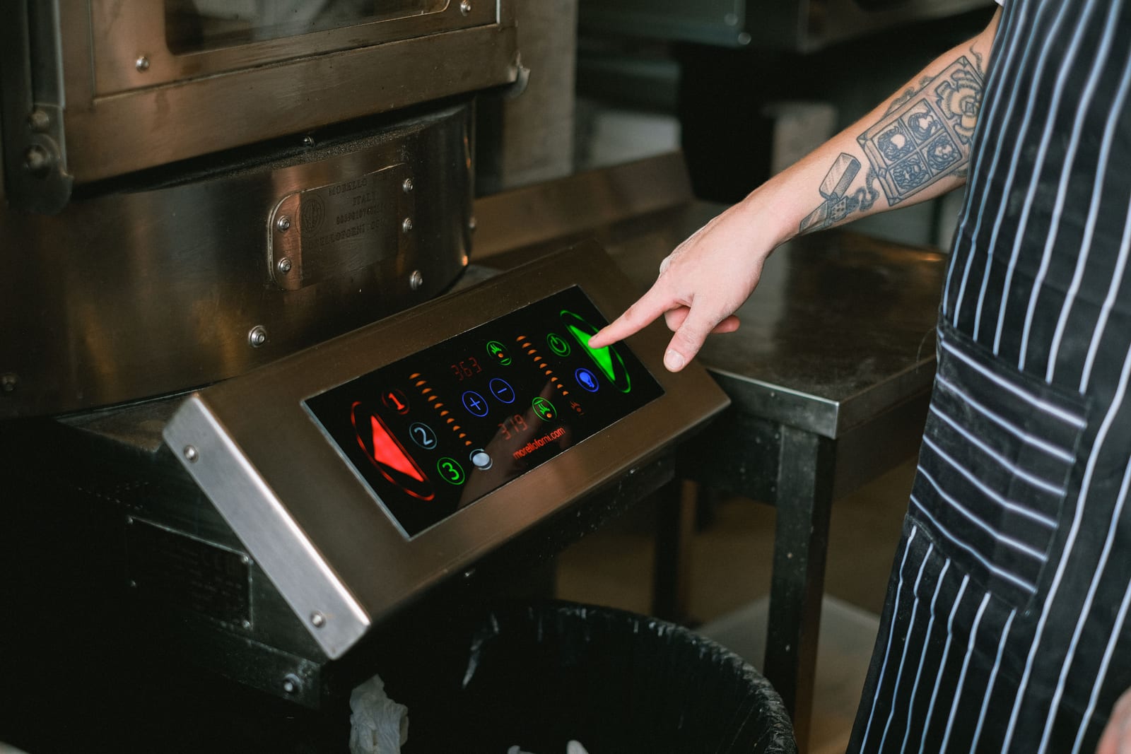 Close-up of a chef using a touchscreen control panel in a modern kitchen.